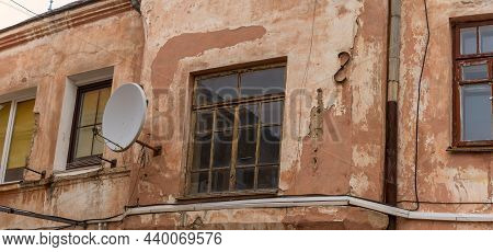A Fragment Of An Old Building With A Round Satellite Dish On The Wall. Windos On Rear Facade Of Hous