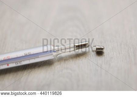 Close-up Of Broken Glass Mercury Thermometer Lying On Floor. Crashed Medical Equipment. Mercury Pois