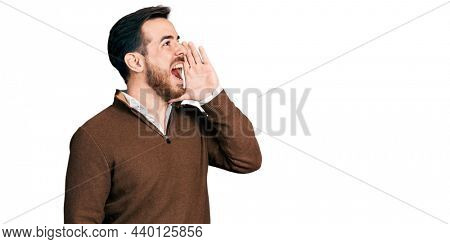 Young hispanic man wearing casual clothes shouting and screaming loud to side with hand on mouth. communication concept. 