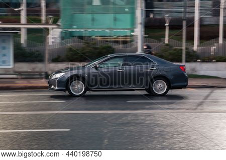 Fast Moving Toyota Camry Xv50 Rides On A Wet City Road. Black Sedan Car On Slippery Road In Motion. 