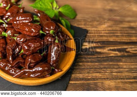 Chili Pepper On Wooden Background.extra Hot Chili. Naga Bhut Jolokia Chocolate. Exotic Spices. Hot I