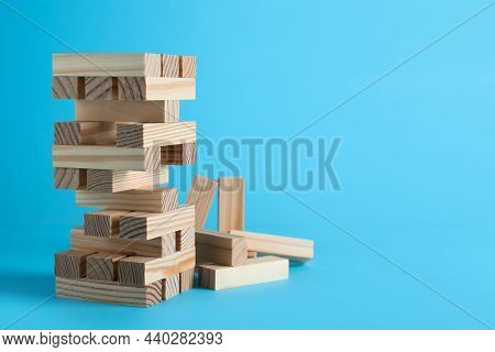 Jenga Tower Made Of Wooden Blocks On Light Blue Background, Space For Text