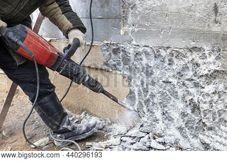 A Worker With A Jackhammer At A Construction Site Levels A Concrete Wall. Powerful Manual Industrial