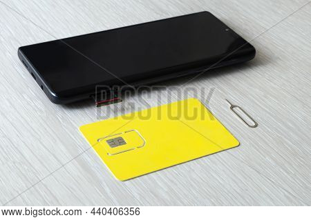 Sim Card And Microsd Card Tray With Removal Tool At The Side Of Smartphone On Wooden Table. Free Spa