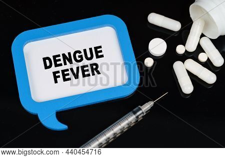Medical Concept. On A Black Surface, A Syringe, Pills And A Blue Frame With The Inscription - Dengue