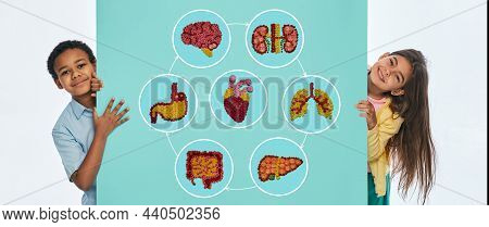 Children Health Concept, Pediatrics. Multi-ethnic Children Near Turquoise Wall With Anatomical Icons