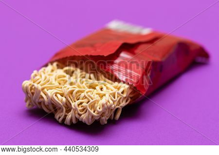 Opened Package With Uncooked Instant Noodles On Violet Background. Raw Pasta. Dry Asian Fast Food. Q