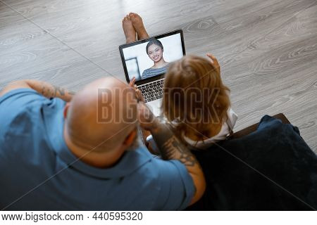 Baldhead Father With Girl Talk To Lady At Videocall Via Modern Laptop Sitting On Floor At Home