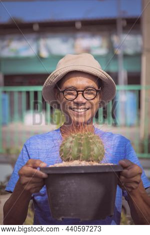 Asian Man Raising Melocactus Pot And Toothy Smiling With Happiness