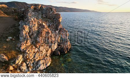 Lake Baikal At Sunset. A Rock With A Hole In The Shape Of A Heart On Cape Tsagan-khushun.