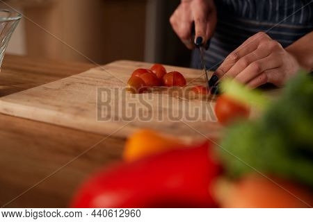 Multi-cultural Young Female Chopping Up Tomatoes On Wooden Chopping Board In Kitchen. Fresh And Heal