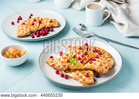 Crispy Croffles With Red Currants, Honey And Mint On Plates, A Cup Of Coffee And Jam On A Light Tabl