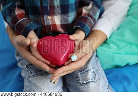 Close-up Of Woman And Child Holding Red Heart On Palms Symbol Of Love. Parent And Son Share Message 