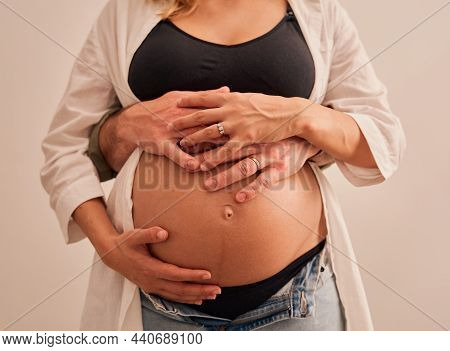 Caucasian Pregnant Women Holding Belly With Husband Standing Behind