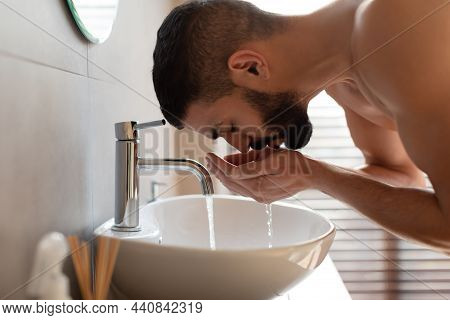 Portrait Of Man Washing His Face At Bathroom