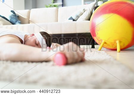 Close-up Of Tired Man Laying On Carpet Floor With Dumbbell Equipment In Hand. Exhausted Sportsman Af