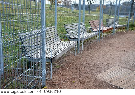 Benches Placed With Their Backs To The Rope Fence, In Front Of A Wire Gray Galvanized Fence Like A C