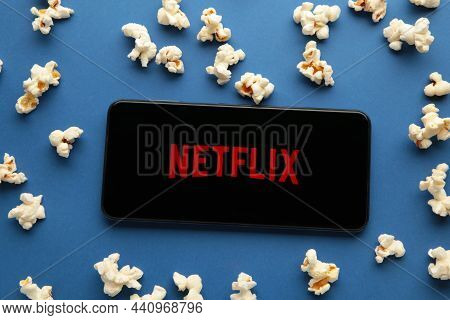 Smartphone With Netflix Logo And Popcorn On Blue Background. Netflix Specializes In And Provides Str