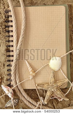 Exercise book and sea stars on sand