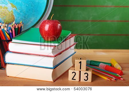 Stack of books, red apple, globe and pencils