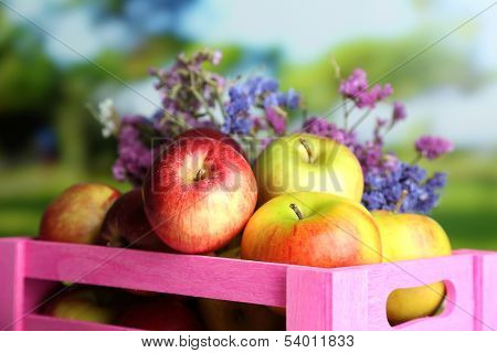 Juicy apples in box on white wooden table on natural background