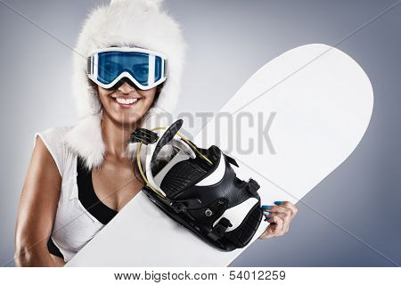 Beautiful young female snowboarder with white fur hat 