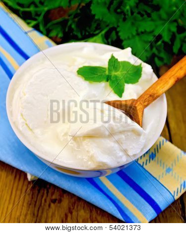 Yogurt In A White Bowl With A Wooden Spoon And Mint