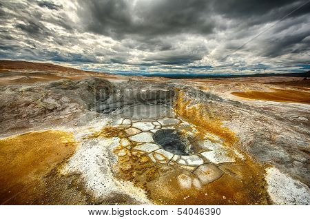 Mudpots in the geothermal area Hverir, Iceland. The area around the boiling mud is multicolored and cracked. HDR image