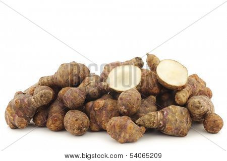 bunch of topinambur roots (helianthus tuberosus) and a cut one on a white background