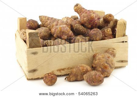 bunch of topinambur roots (helianthus tuberosus) in a wooden crate on a white background