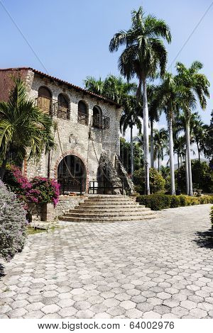 Vertical image of the grand entrance to the beautiful Ogier-Fombrun Museum in Montrouis, Haiti.  It is set among majestic palms and colorful foliage.  