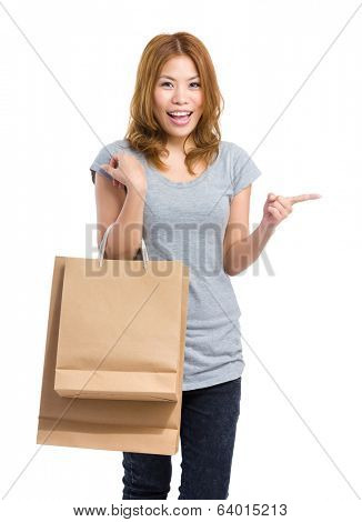 Asian woman with shopping bag and finger pointing aside