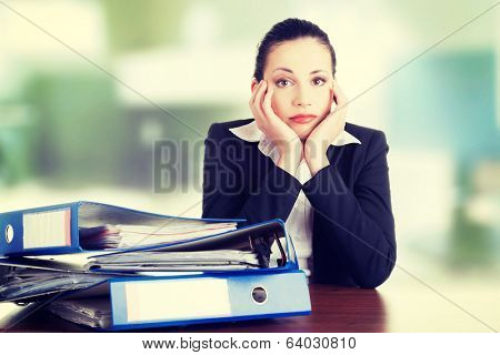 Sad woman with ringbinders sitting at the desk. Tired and exhousted business woman. 