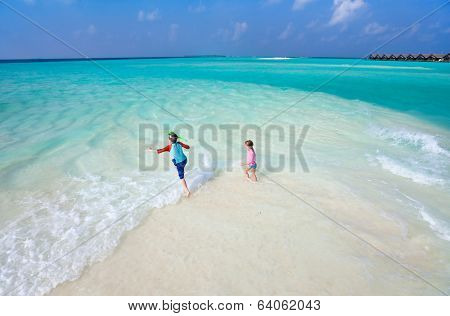 Above view of a stunning tropical ocean and white sand beach with kids plashing at shore
