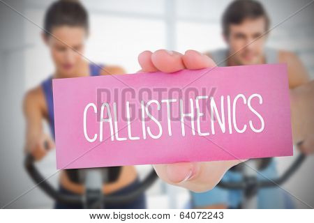 Woman holding pink card saying callisthenics against class in gym