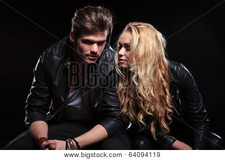 young man and woman sitting next to each other, the man is looking into the camera. on black background