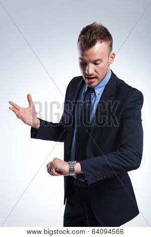 young business man looking unpatiently at his wrist watch. on a light gray studio background
