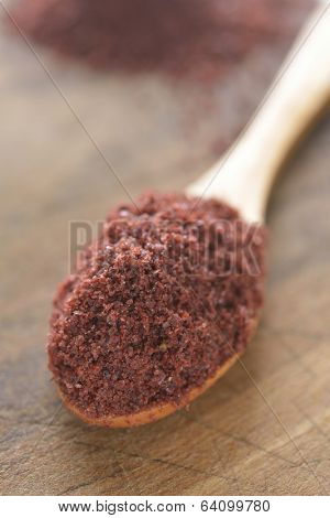 Sumak in a wooden spoon. Selective focus on the spice