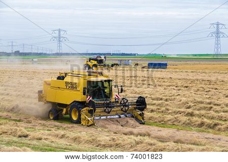Dutch Farmers With Agricultural Machinery Harvesting A Wheat Field