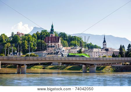 Electric Locomotive Crossing The Bridge In Fron Of Pfarramt Mulln Catholic Church In Salzburg