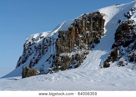 Arktic. Cliffs Protruding From The Snow.