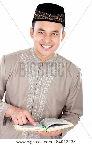 Young Muslim Man With Finger Pointing At The Quran