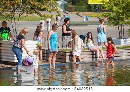 Adults And Children Standing On The Shore Of A Pond