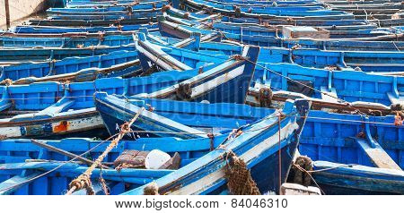 Many blue empty fishing boats tied next to eath other