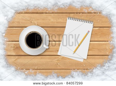 Coffee, pencil and notebook on the planks covered with snow