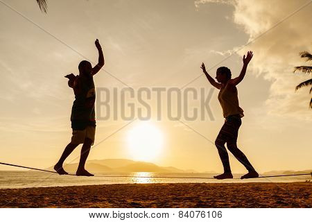 Teenage Couple Balancing Slackline On The Beach