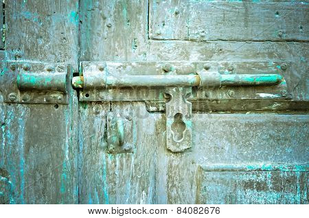 Rusted keyhole on green wooden door