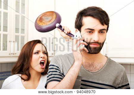 Young rage woman hitting her talking partner with frying pan.