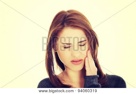 Teen woman pressing her bruised cheek with a painful expression as if she's having a terrible tooth ache.