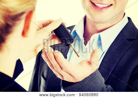 Car salesman handing over the keys for a new car to a young businessman